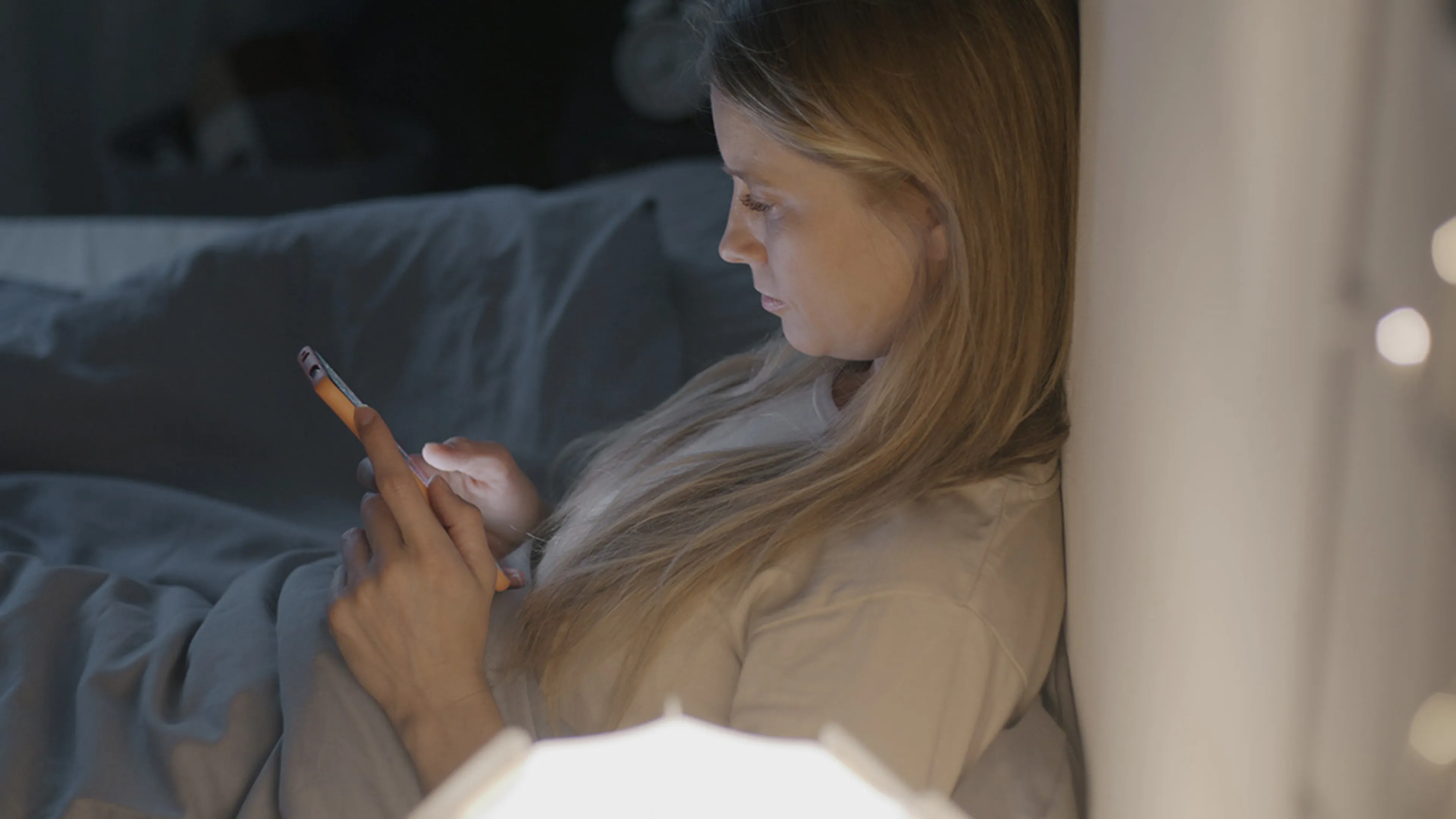 Een vrouw zit op haar smartphone. We brengen veel tijd door op sociale media.