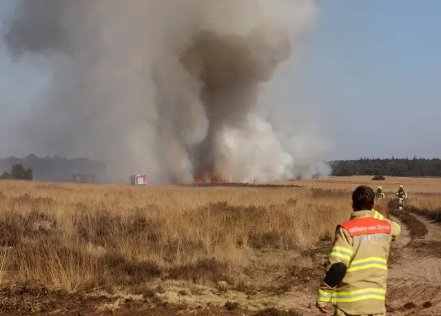 brandweerman kijkt naar grote brand op de heide in Ede, die is ontstaan tijdens een oefening van Defensie.