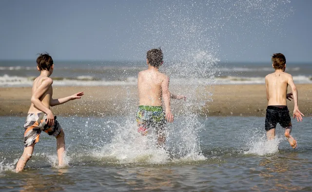 Kinderen spelen op het strand in de zon. Uit onderzoek blijkt dat ouders hun kinderen onvoldoende beschermen tegen de zon, met als risico op huidkanker.