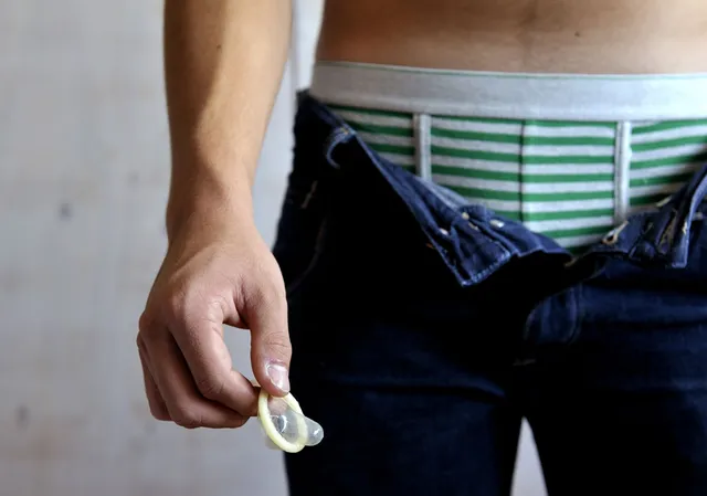 Een man met een condoom in zijn hand.