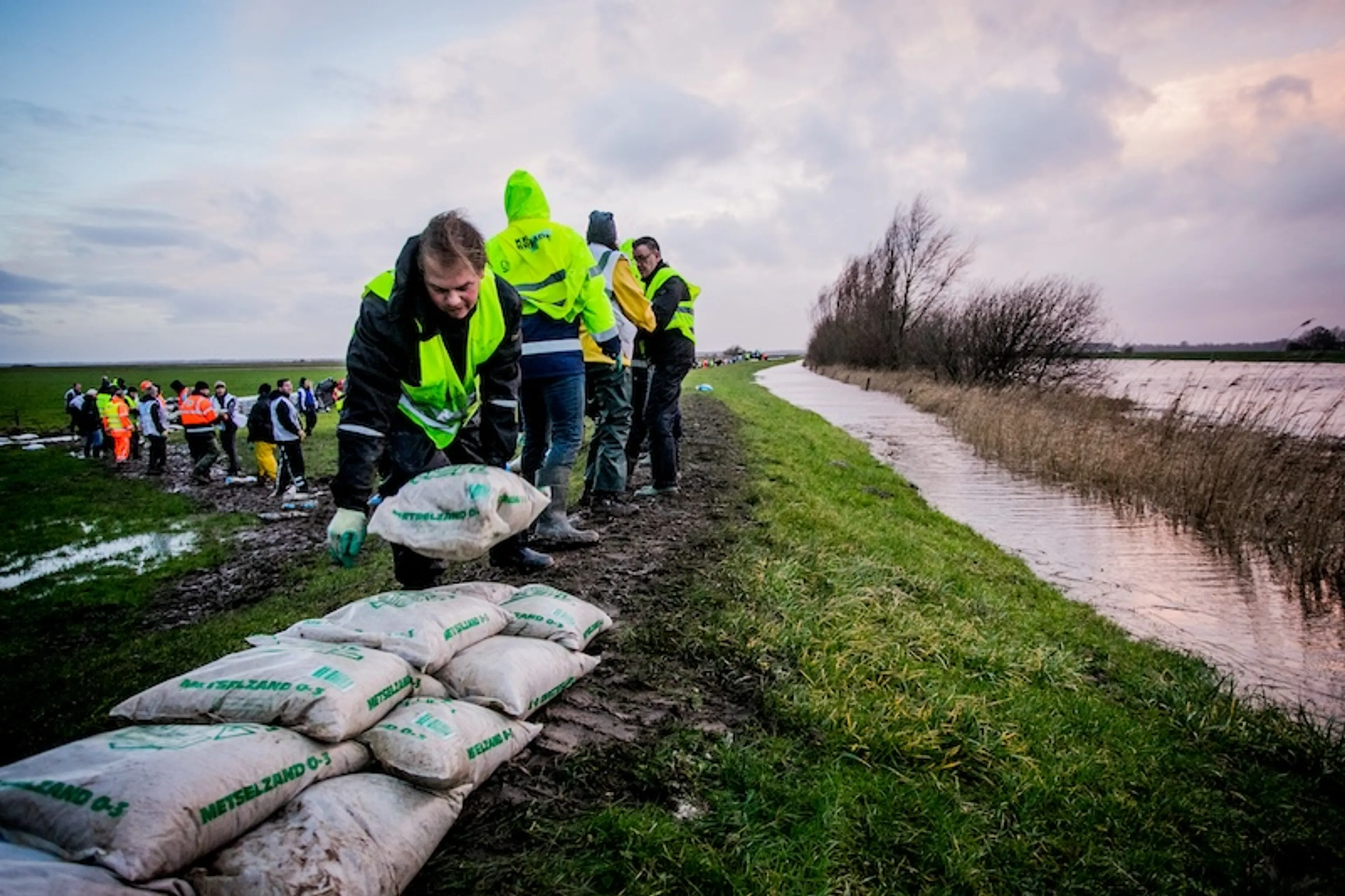 Vrijwilligers leggen zandzakken neer bij de dijken bij de Kampereilanden. Vanwege het hoogwater in en rond Kampen had het waterschap Drents Overijsselse Delta in 2018 inwoners opgeroepen om te komen helpen met het vullen en leggen van zandzakken.
