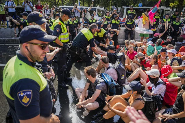Je ziet hier politie tegenover demonstranten van Extinction Rebellion op de A12. De demonstranten zitten op de grond.